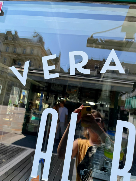 Laca Typeface on a pizzeria shop window in Vienna. The photographer, Joana, is reflected in the glass, and you can also see inside the shop. Text: "VERA."
